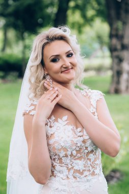 Gelinlik ve duvak takmış, dışarıda poz veren güzel mutlu genç gelinin portresi           