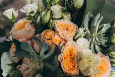 Yüzüklerin yakın görüntüsü ve güzel çiçekli düğün buketi.            