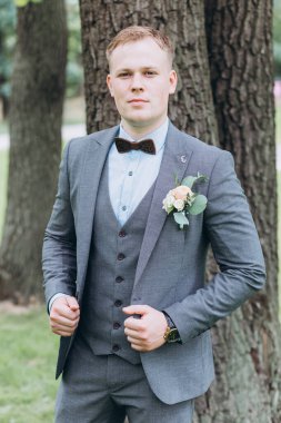 Parkta duran yakışıklı, şık genç damadın portresi.       