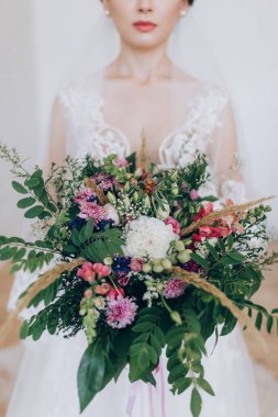 Güzel genç gelin elinde bir buket çiçek tutuyor. 