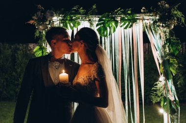 Düğün töreninde ellerinde mum tutan genç bir çift.