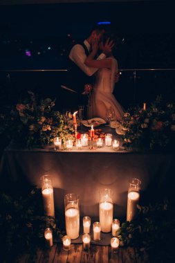 Gelin ve damat mum ışığında öpüşüyor.