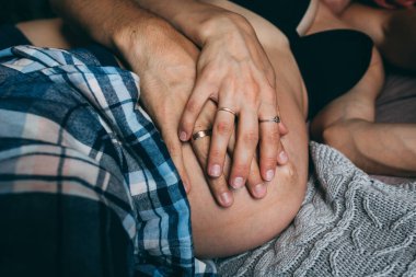 Hamile çift sarılıyor ve karnına dokunuyor. 