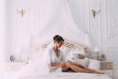 Yatakta poz veren güzel genç bir kadın, gelinin sabahı....       