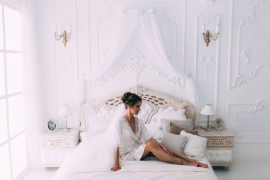 Yatakta poz veren güzel genç bir kadın, gelinin sabahı....       