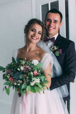 Mutlu ve şık gelin ve damat düğün salonunda buketle                   