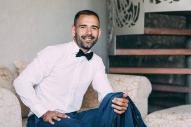 Takım elbiseli ve papyonlu yakışıklı damadın portresi.                 