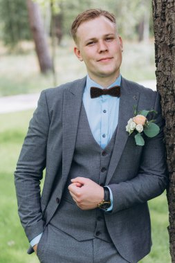 Parkta duran yakışıklı, şık genç damadın portresi.       