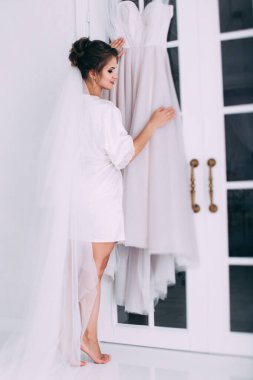 Evde beyaz gelinlikle poz veren güzel mutlu genç gelinin portresi.        