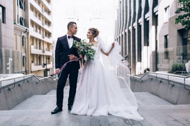 Güzel mutlu gelin ve damat düğün gününde şehirde poz veriyor.    