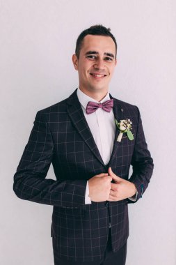 Takım elbiseli ve papyonlu yakışıklı damadın portresi.                 