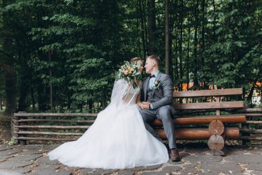 Mutlu gelin ve damat parkta bankta oturmuş