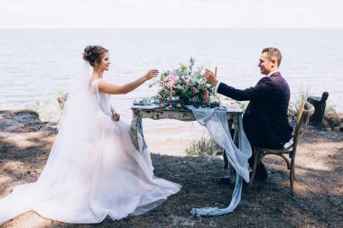 Genç ve güzel bir çift kumsalda masada oturuyor.