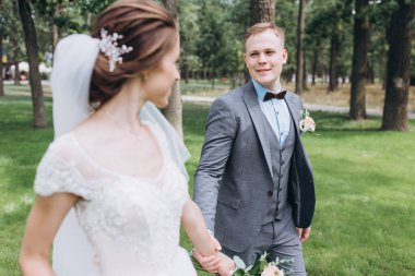 Güzel, mutlu gelin ve damat parkta yürüyor..   