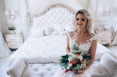 Gelinlikli güzel bir kadın yatak odasında poz veriyor.   