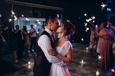 Genç ve güzel gelin ve damat gece dans edip öpüşüyor. 