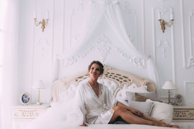 Yatakta poz veren güzel genç bir kadın, gelinin sabahı....       