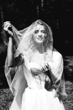 Gelinlik ve duvak takmış, dışarıda poz veren güzel mutlu genç gelinin portresi           