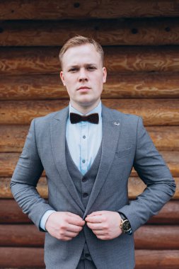 Ahşap duvarda duran takım elbiseli yakışıklı damadın portresi.             