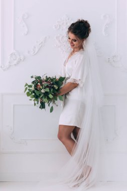 Stüdyoda çiçek demeti ile poz veren peçeli güzel gelinin portresi..