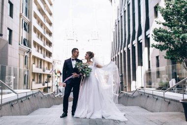 Güzel mutlu gelin ve damat düğün gününde şehirde poz veriyor.    