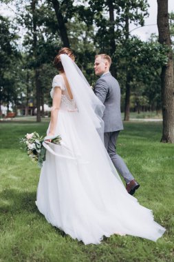 Güzel, mutlu gelin ve damat parkta yürüyor..   