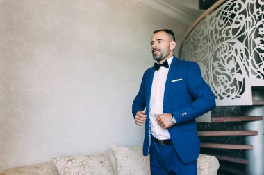 Takım elbiseli ve papyonlu yakışıklı damadın portresi.                 