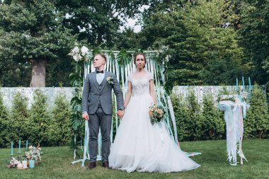 Damat ve güzel kemerli mutlu genç gelin açık hava düğün töreninde    