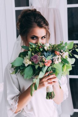 Genç, mutlu gelin ve bir buket çiçekle düğün içinde poz veriyor.         