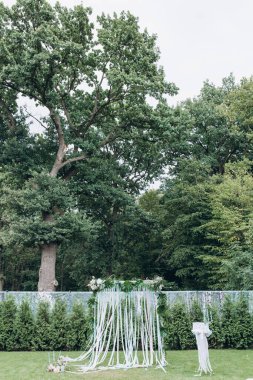 Çiçeklerle süslenmiş güzel kemerli açık hava düğün töreni. 