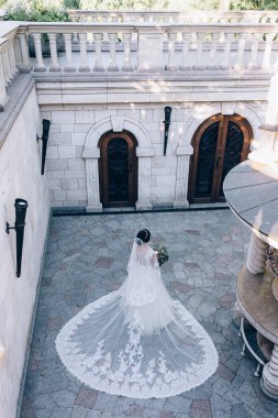 Gelinlik ve peçeyle eski binaya poz veren güzel genç gelin. 