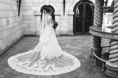 Gelinlik ve duvak giymiş güzel genç gelin eski şehirde poz veriyor.