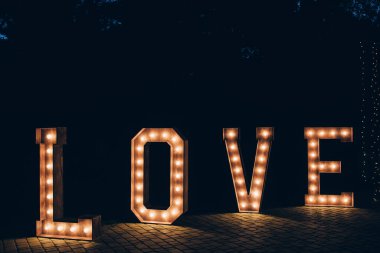 Parlayan harfler, düğün dekorasyonu için ahşap arka planda aşk kelimesi. 