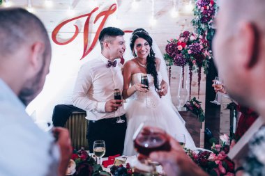 Genç mutlu yeni evliler düğün resepsiyonunda şarap içiyorlar.                 