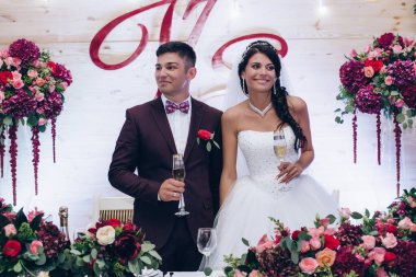 Genç mutlu yeni evliler düğün resepsiyonunda şarap içiyorlar.                 