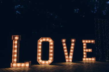 Parlayan harfler, düğün dekorasyonu için ahşap arka planda aşk kelimesi. 
