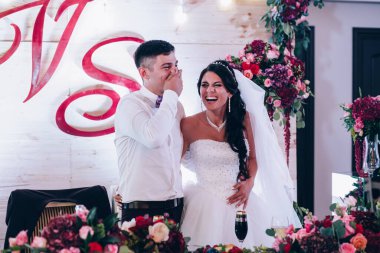 Güzel, genç, mutlu yeni evliler düğün resepsiyonunda gülüyorlar.     