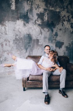 Mutlu gelin ve damat stüdyoda kanepede oturuyor. 