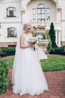 Gelinlik içindeki genç gelin elinde güzel bir buket çiçek tutuyor.                  