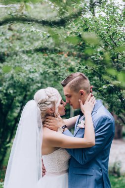 Güzel mutlu genç damat ve gelin parkta poz veriyor, düğün günü.             