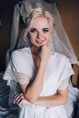 Genç, güzel sarışın gelin otel odasında yatakta poz veriyor.