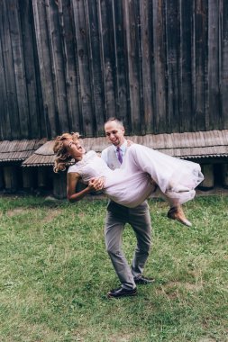 Mutlu genç gelin ve damat düğün günü dışarıda eğleniyor ve gülüyorlar.            