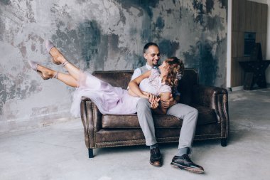 Mutlu gelin ve damat stüdyoda kanepede oturuyor. 