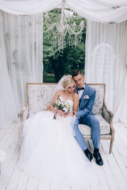 Güzel genç gelin ve damat düğün günü birlikte oturup sarılıyorlar..             