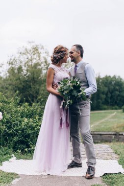 Güzel mutlu genç damat ve gelin parkta poz veriyor, düğün günü.             