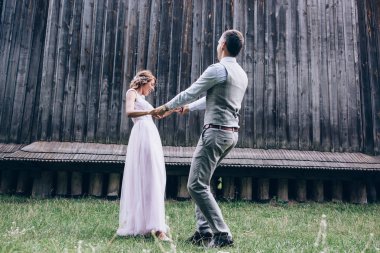 Mutlu genç gelin ve damat düğün günü dışarıda eğleniyor ve gülüyorlar.            