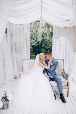 Güzel genç gelin ve damat düğün günü birlikte oturup sarılıyorlar..             