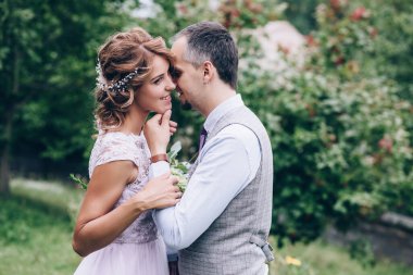 Güzel bir çift gelin ve damat doğada kucaklaşıyorlar.