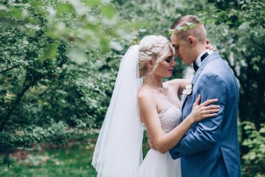 Güzel mutlu genç damat ve gelin parkta poz veriyor, düğün günü.             