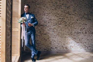 Genç yakışıklı adam gelinlik içinde poz veriyor.